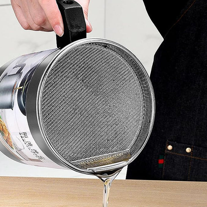 Person pouring oil from a can into a frying pan with a mesh lid.