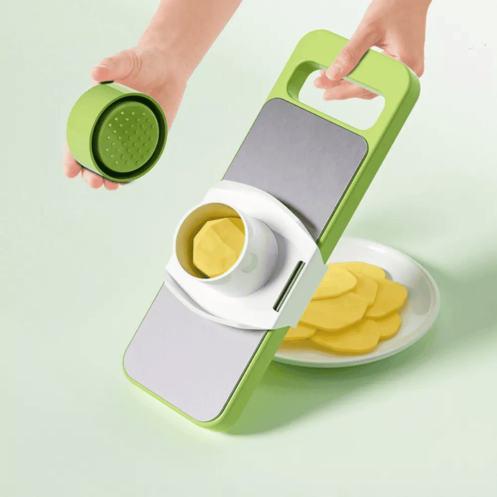 Green and white vegetable chopper with sliced vegetables on a light green background