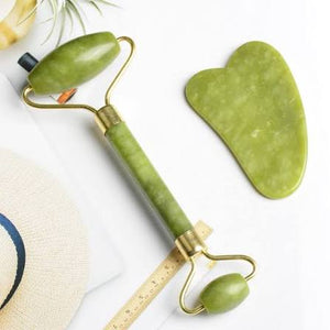 Green facial roller and gua sha tool on a white background
